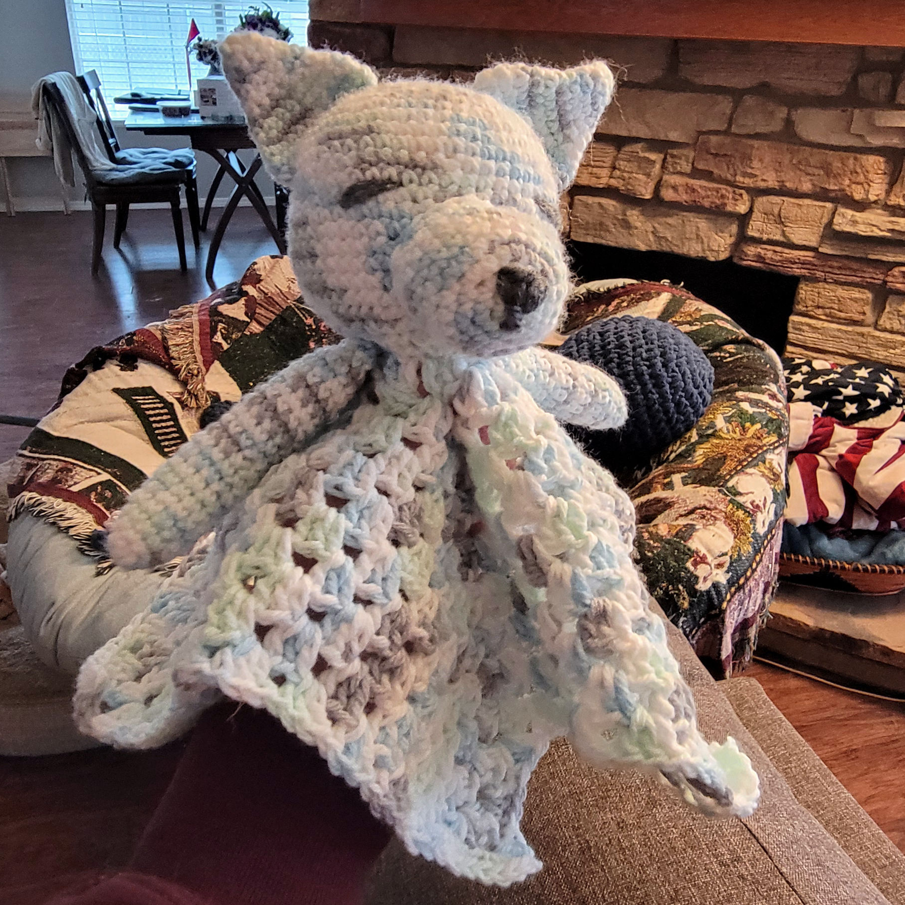 Crochet wolf lovey in a variegated yarn: blue, green, white, and grey