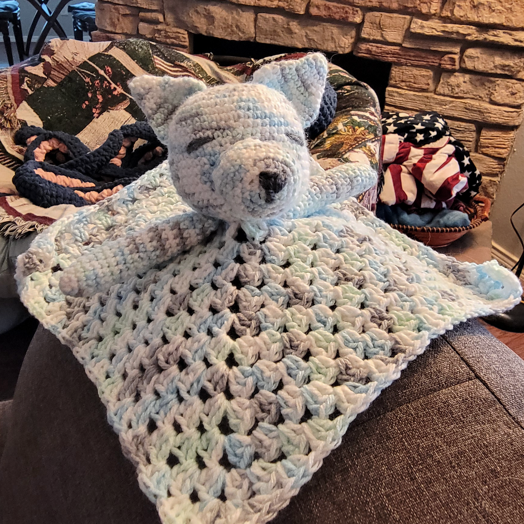 Crochet wolf lovey in a variegated yarn: blue, green, white, and grey