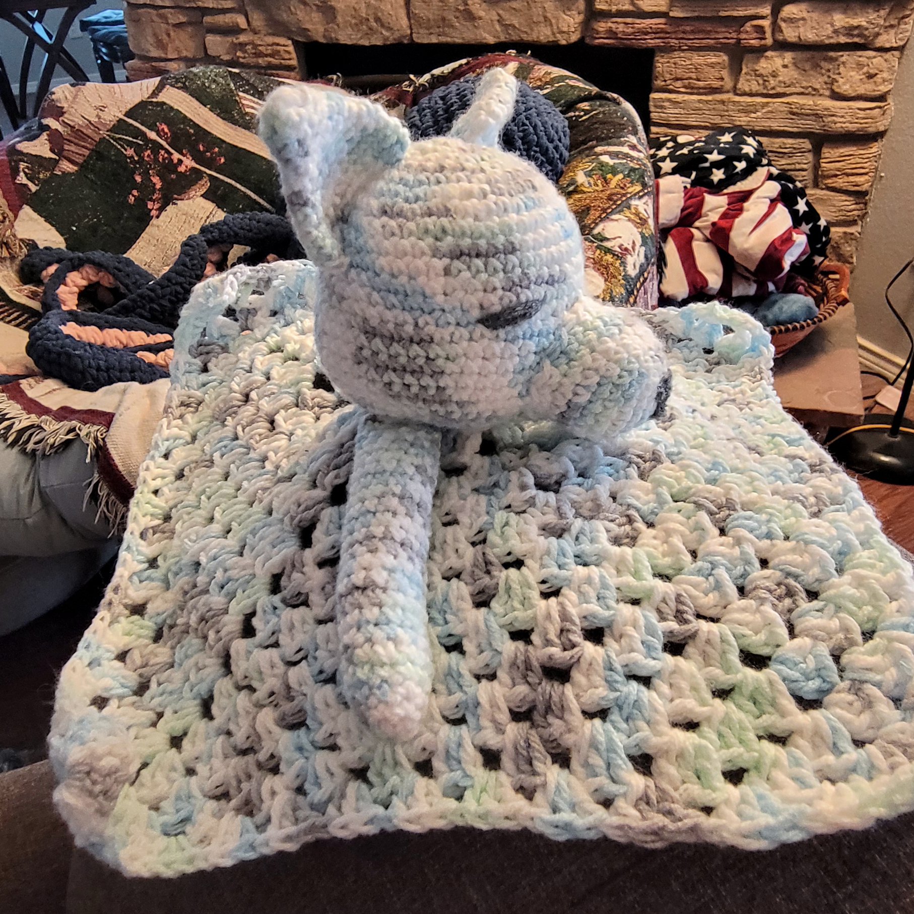 Crochet wolf lovey in a variegated yarn: blue, green, white, and grey