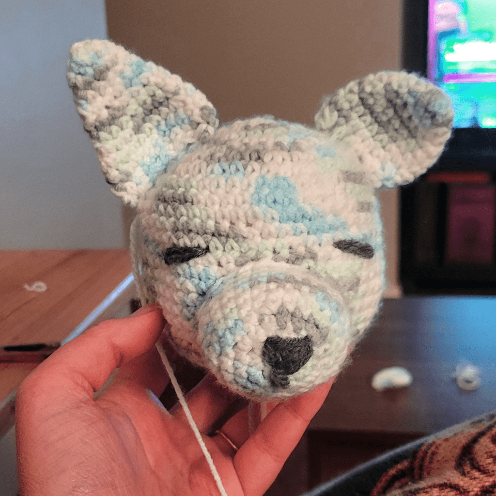 Crochet wolf head in a variegated yarn: blue, green, white, and grey